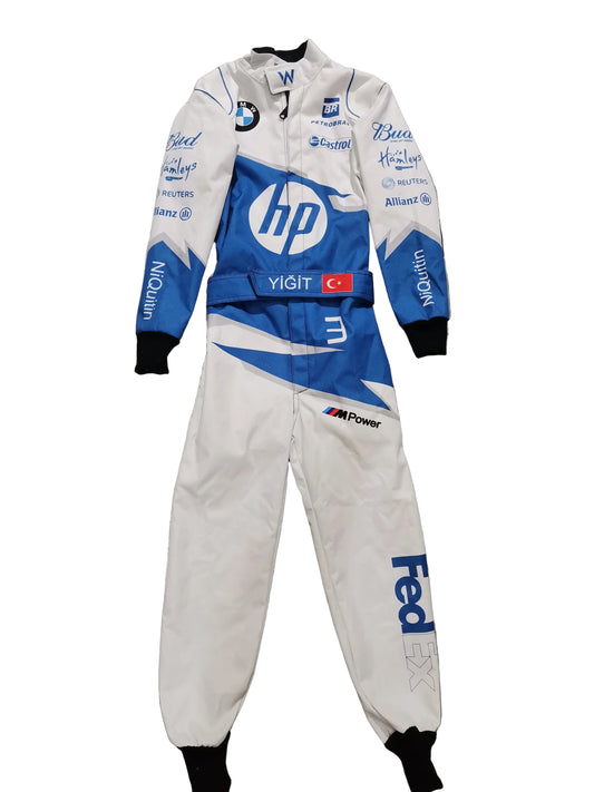 A white and blue racing suit laid flat on a gray marble-patterned tile floor. The suit features prominent sponsor logos including HP, FedEx, BMW, and others, along with a small Turkish flag patch on the chest.