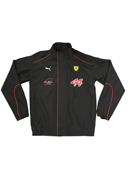 A black Puma Ferrari racing jacket with red piping, the Scuderia Ferrari logo, and the number 44, laid flat on a blue sheet.