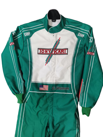 A green and white Tony Karl / G. Stamm racing suit laid flat on a black background.