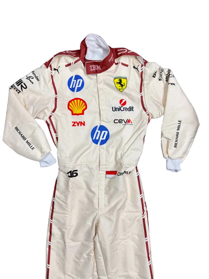 A cream-colored Scuderia Ferrari racing suit by Richard Mille, featuring multiple sponsor logos including HP, Shell, and Unipred, laid flat on a dark blue blanket.